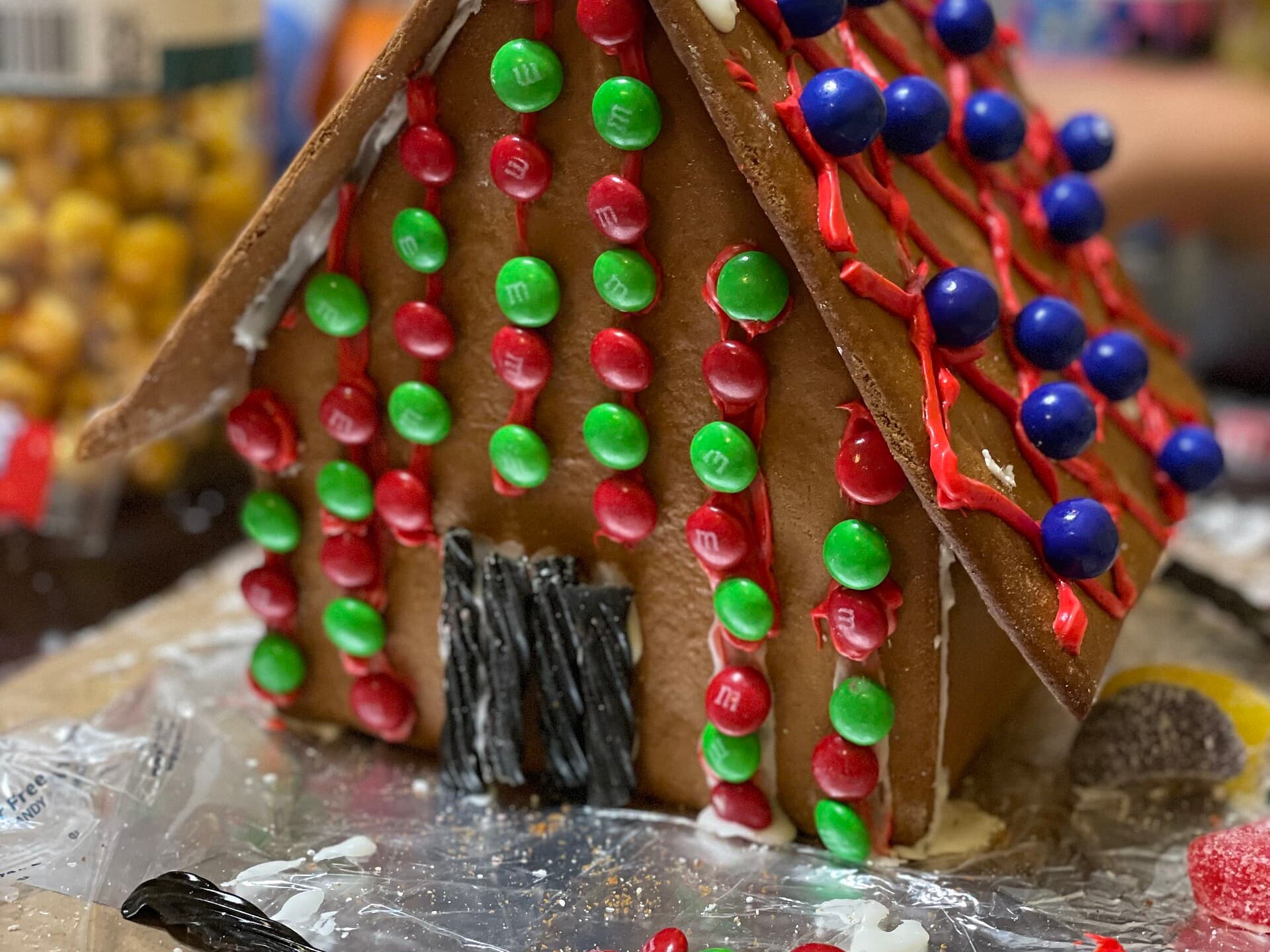 Amerikanisches Lebkuchenhaus mit roten, grünen und blauen Schokolinsen und Lakritzstreifen verziert
