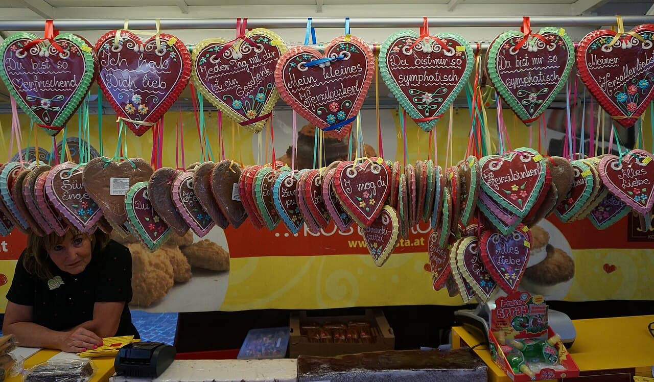 Marktstand mit einer Reihe verzierter Lebkuchenherzen, darauf Sprüche wie „I mog di“ und „Herzbinkerl“