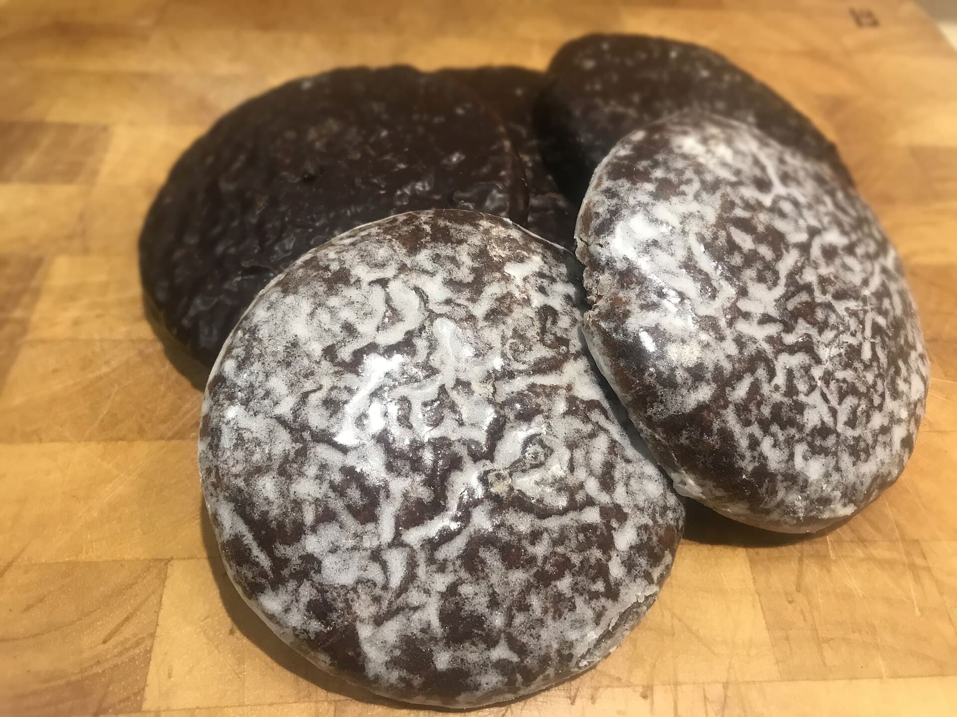 Ein Stapel runder Nürnberger Lebkuchen, mit Zuckerglasur und mit dunkler Schokolade, auf einem Holzbrett