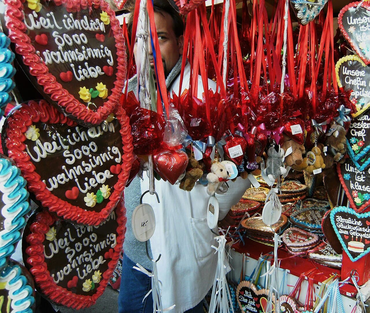 Verkaufsstand auf dem Oktoberfest in München mit großen Lebkuchenherzen, auf denen „Weil ich dich sooo wahnsinnig liebe“ steht