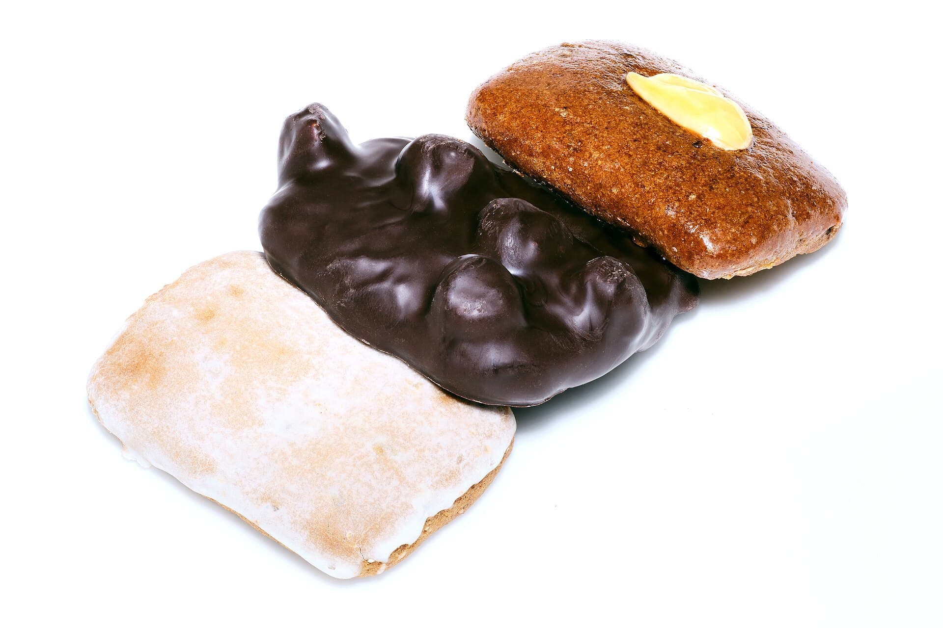Drei Aachener Printen: eine mit weißer Zuckerglasur, eine mit Nüssen und Schokolade überzogen, eine braune mit heller Verzierung