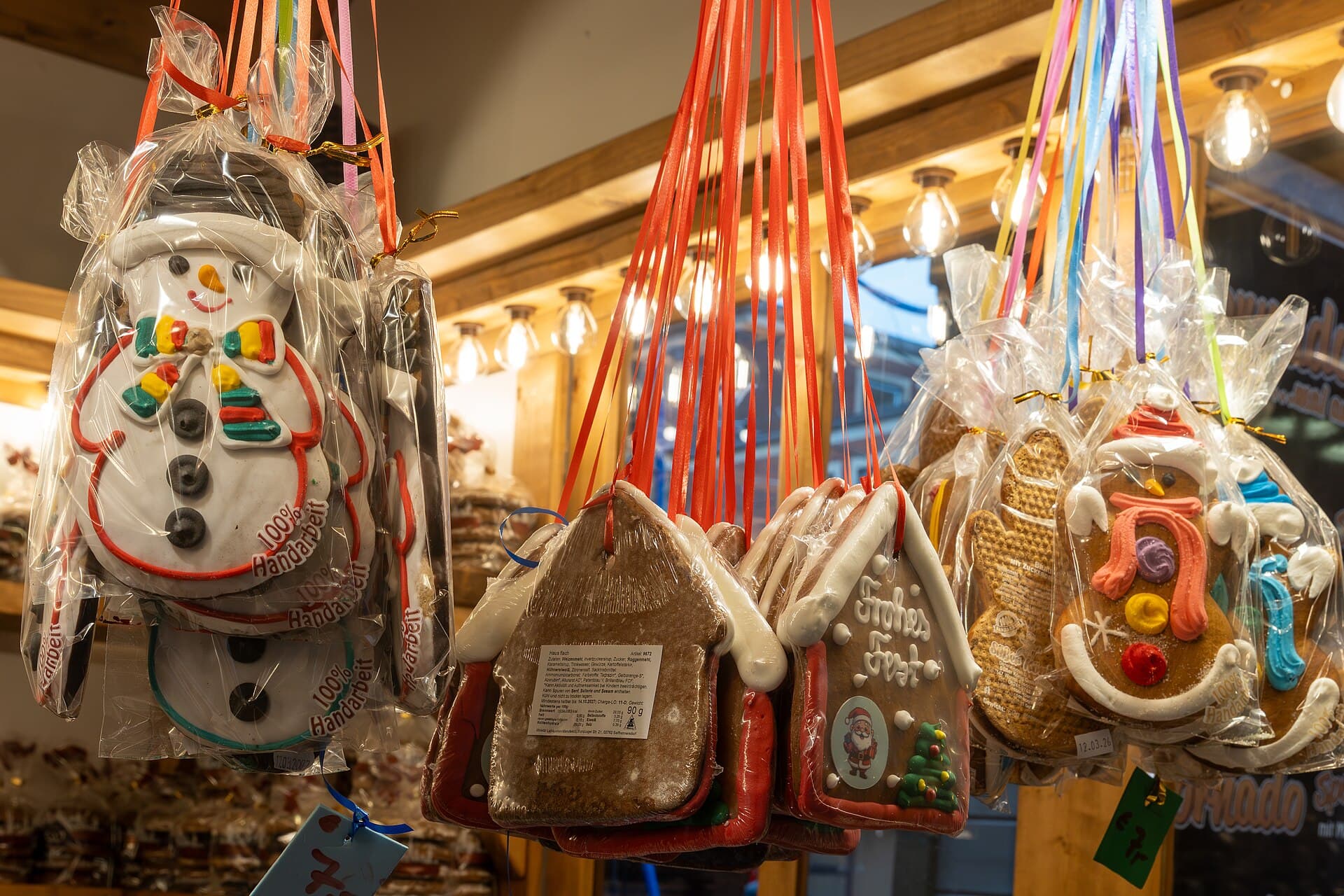 Verpackte Lebkuchenfiguren als Schneemann und Haus hängen an bunten Bändern an einem Stand auf dem Weihnachtsmarkt in Münster